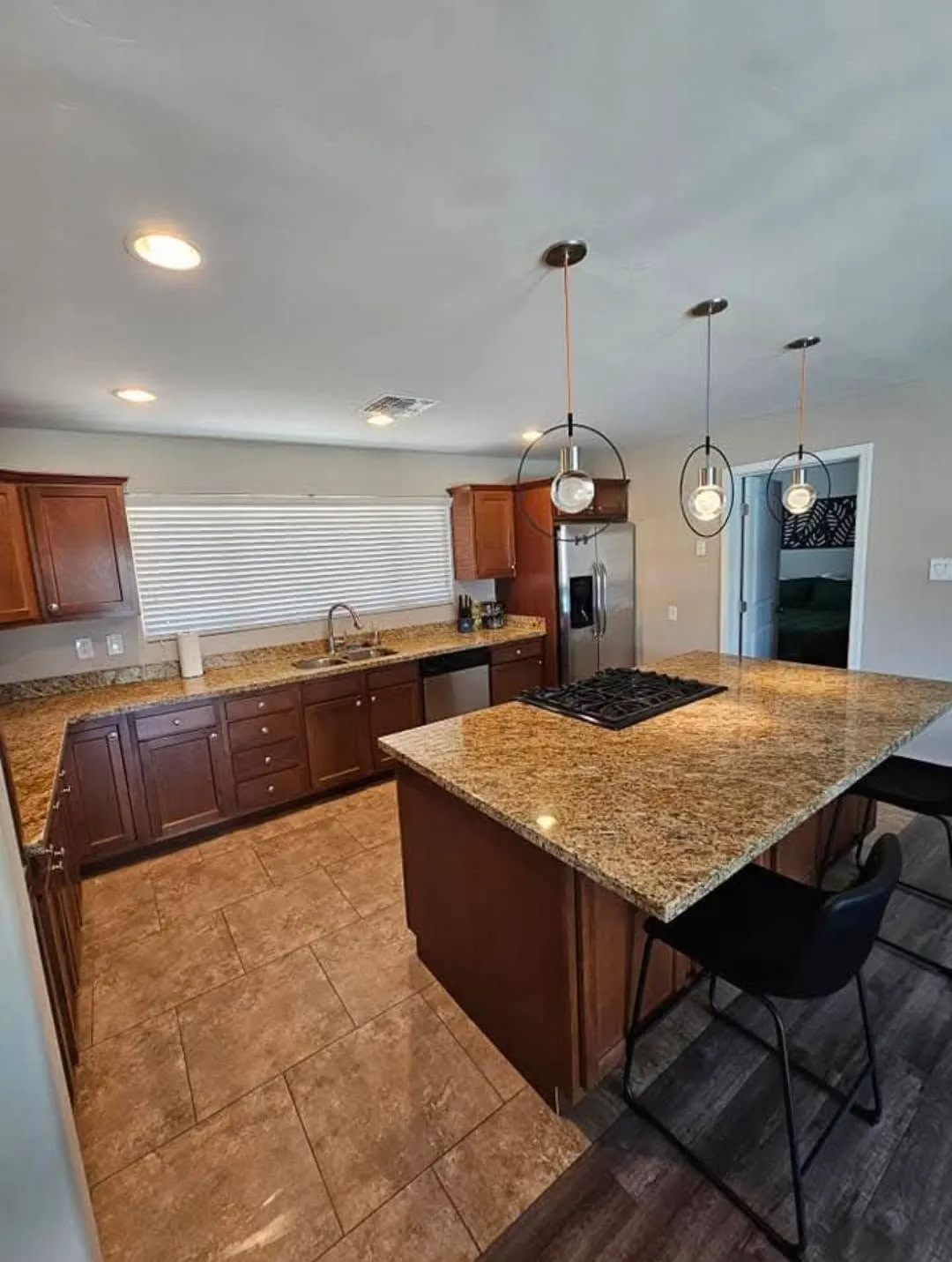 Clean kitchen with granite island, cooktop, and pendant lights from a New Star appointment