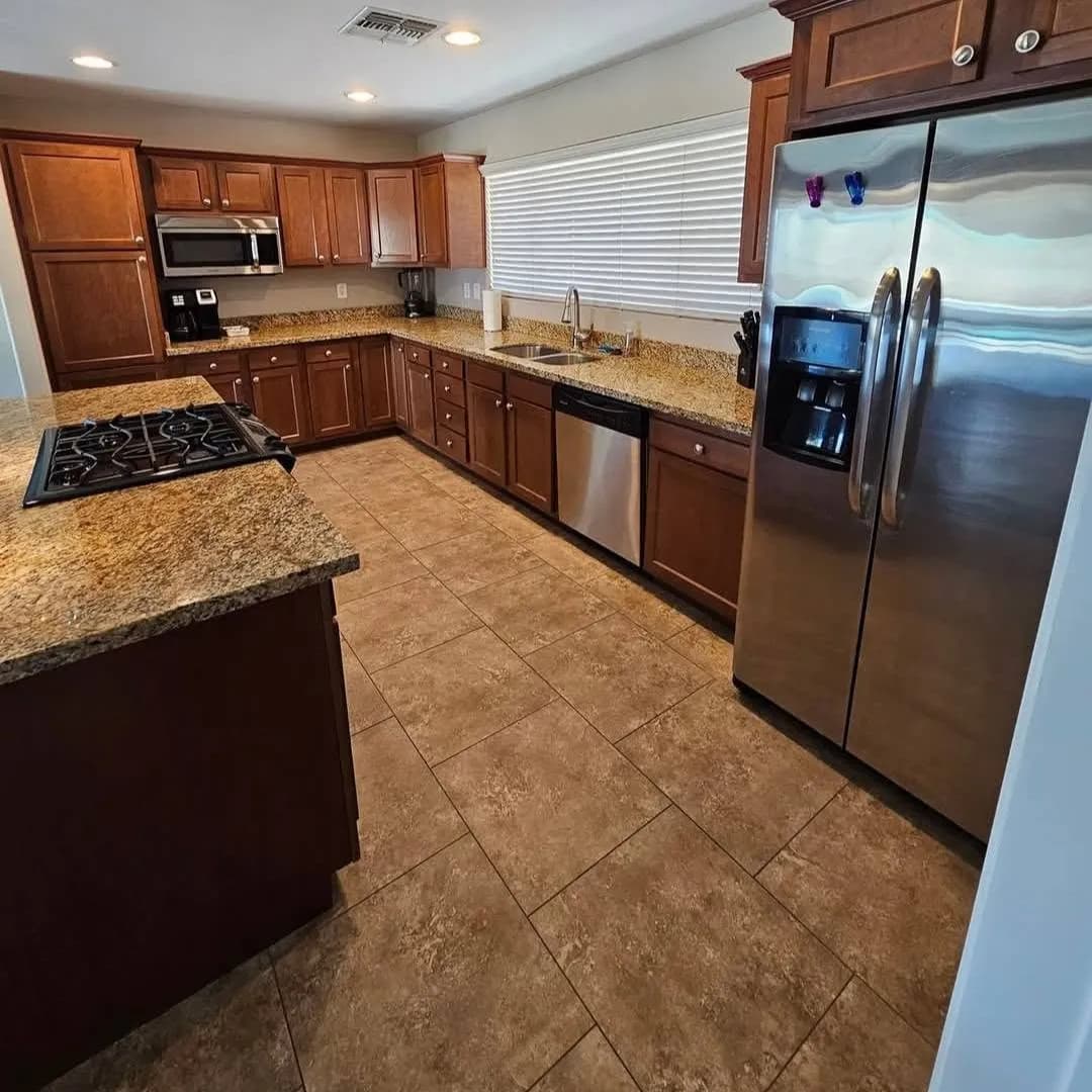 Kitchen with wood cabinets, granite counters, stainless appliances, and a tile floor