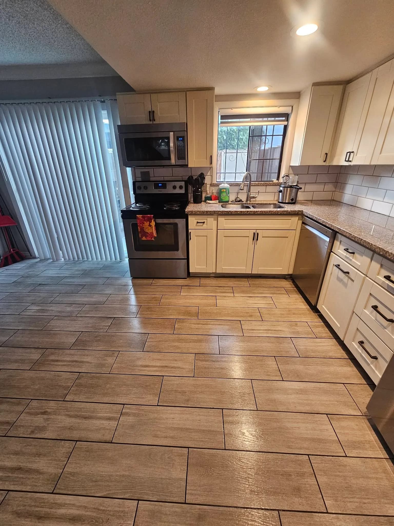 Clean empty-home kitchen with white cabinets and wood-look tile floor from a New Star appointment