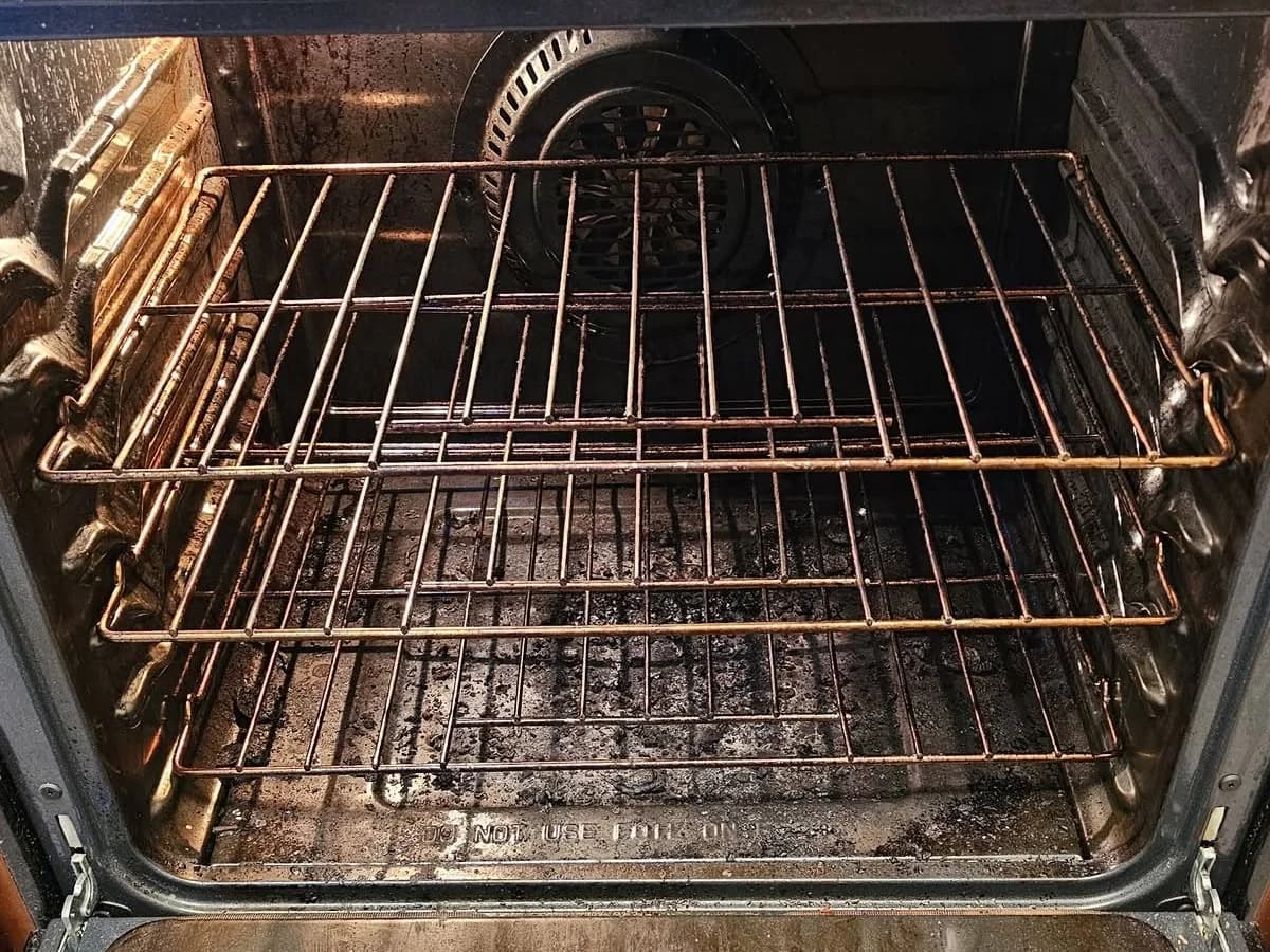 Oven interior with burnt residue on the racks and floor before cleaning
