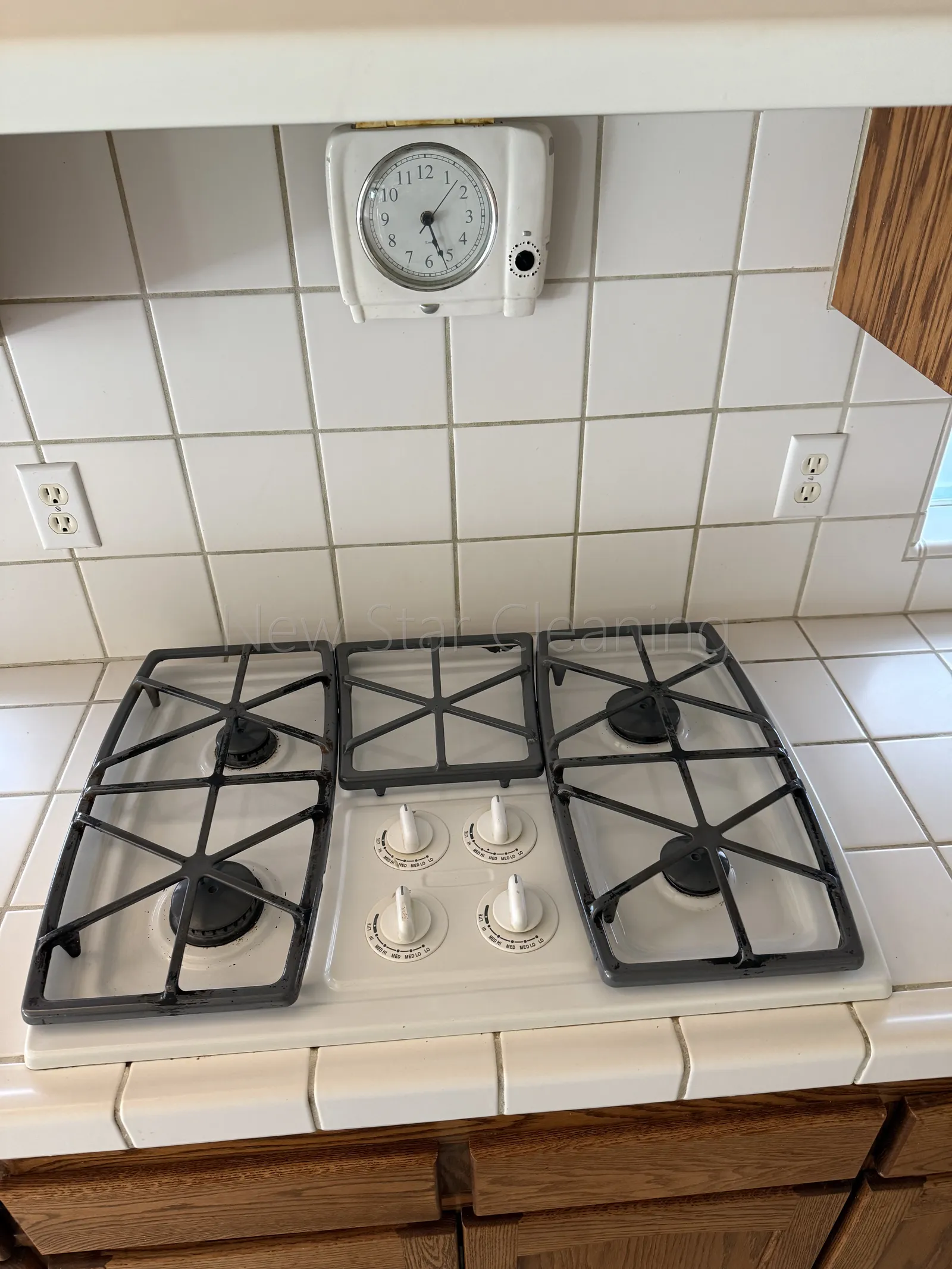The same gas cooktop with visibly cleaner enamel, knobs, and grates after New Star detail work