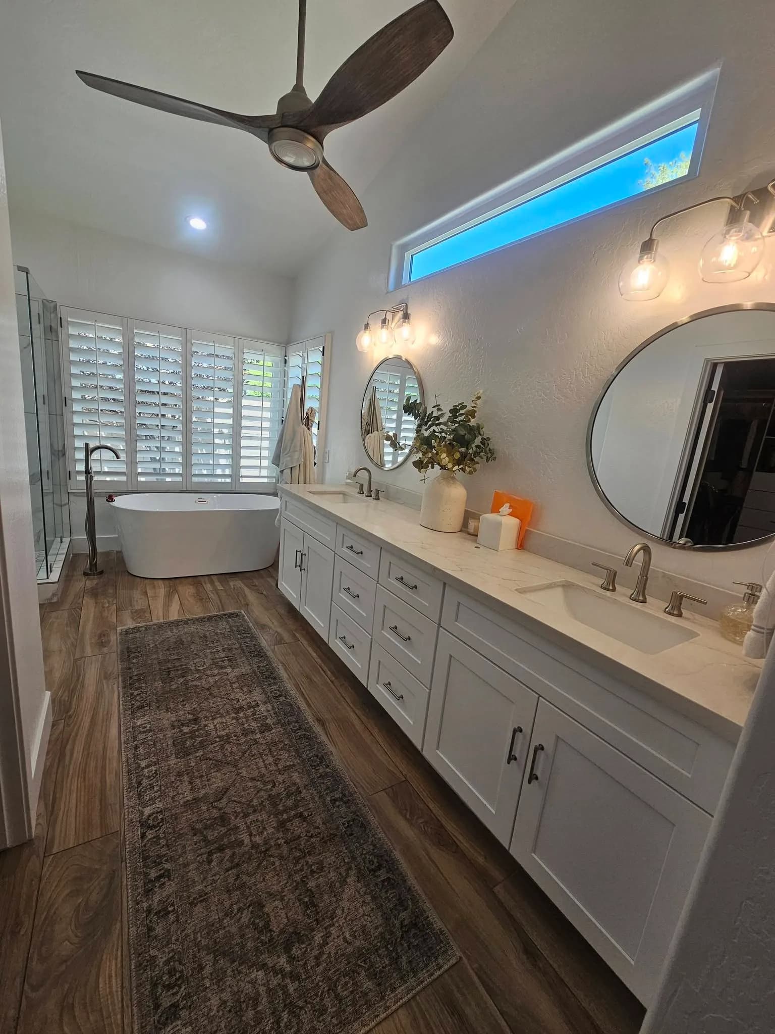 Finished primary bathroom with freestanding tub, double vanity, and wood-look floor from a New Star appointment