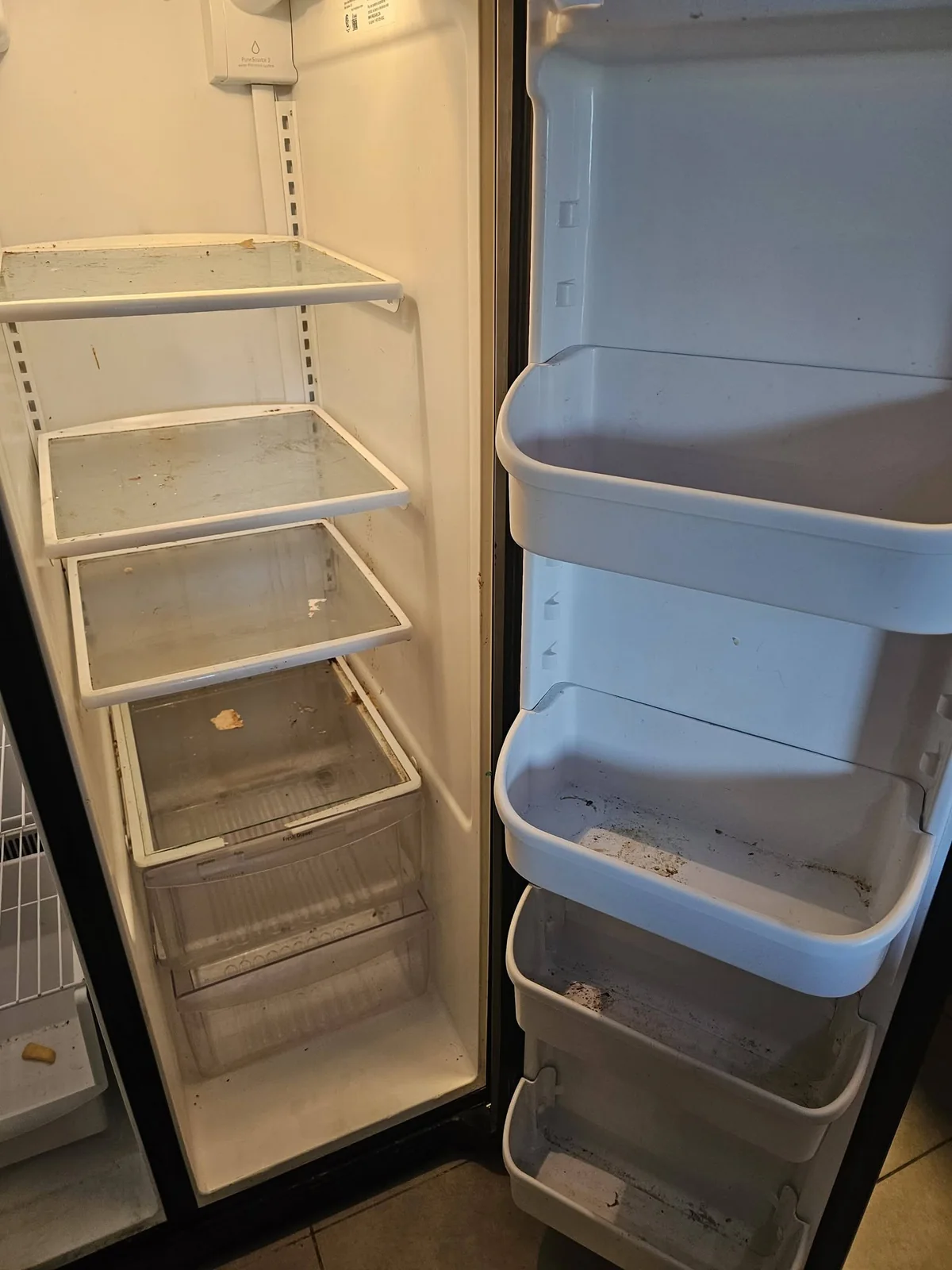 Refrigerator interior with soiled shelves and drawers before cleaning